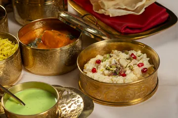 De cerca: un cuenco de kheer con pistacho y granada, y otro de tikka masala