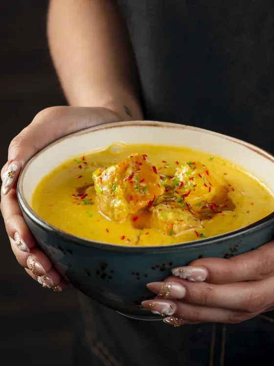 Un cuenco de mango chicken entre las manos de quien lo sirve