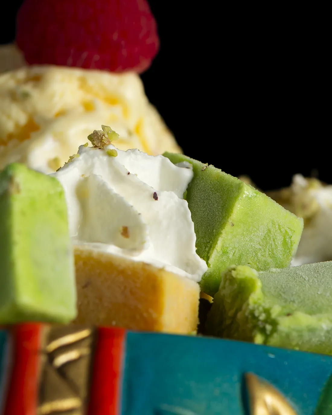 Helado, dulces verdes y una frambuesa servidos sobre un elefante de cerámica turquesa