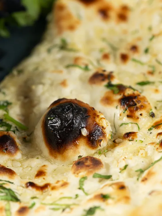 Naan recién salido del horno, tostado y con cilantro por encima